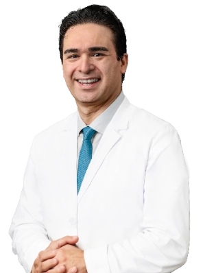 A professional headshot of Dr. Farshid Etaee wearing a white lab coat and a blue tie. He is smiling and posing against a plain white background.